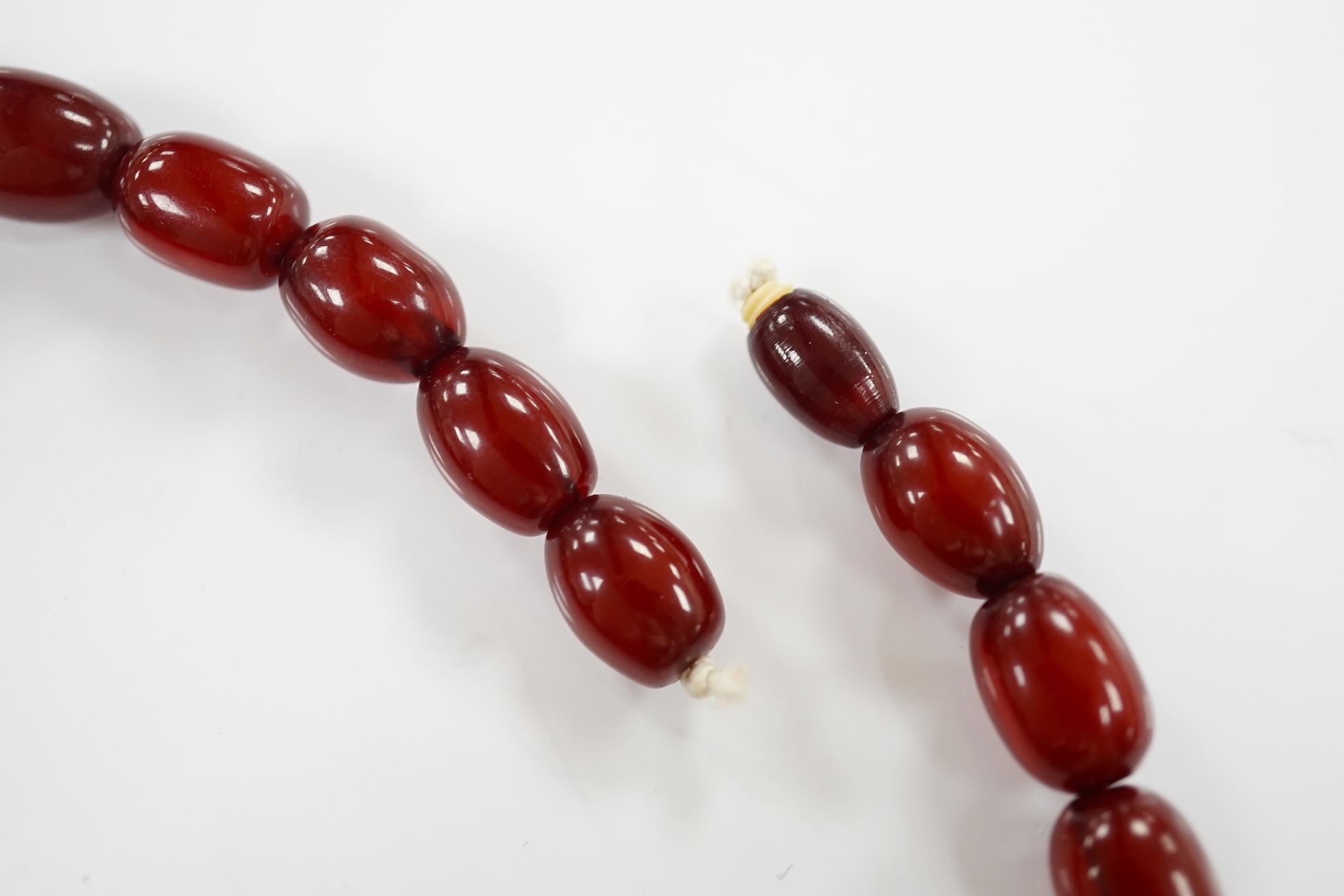 A single strand graduated oval simulated cherry amber bead necklace, 38cm, gross weight 41 grams. Condition - poor to fair